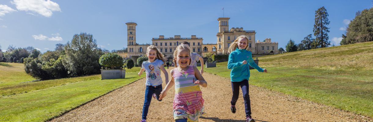 Children running within the grounds of Osborne with Osborne House in the background